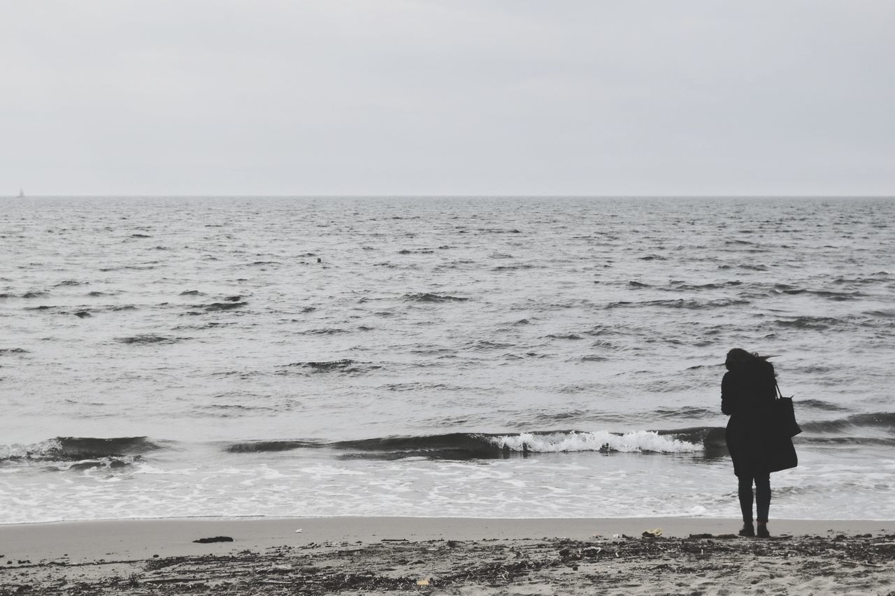 WOMAN WALKING ON BEACH AGAINST CLEAR SKY