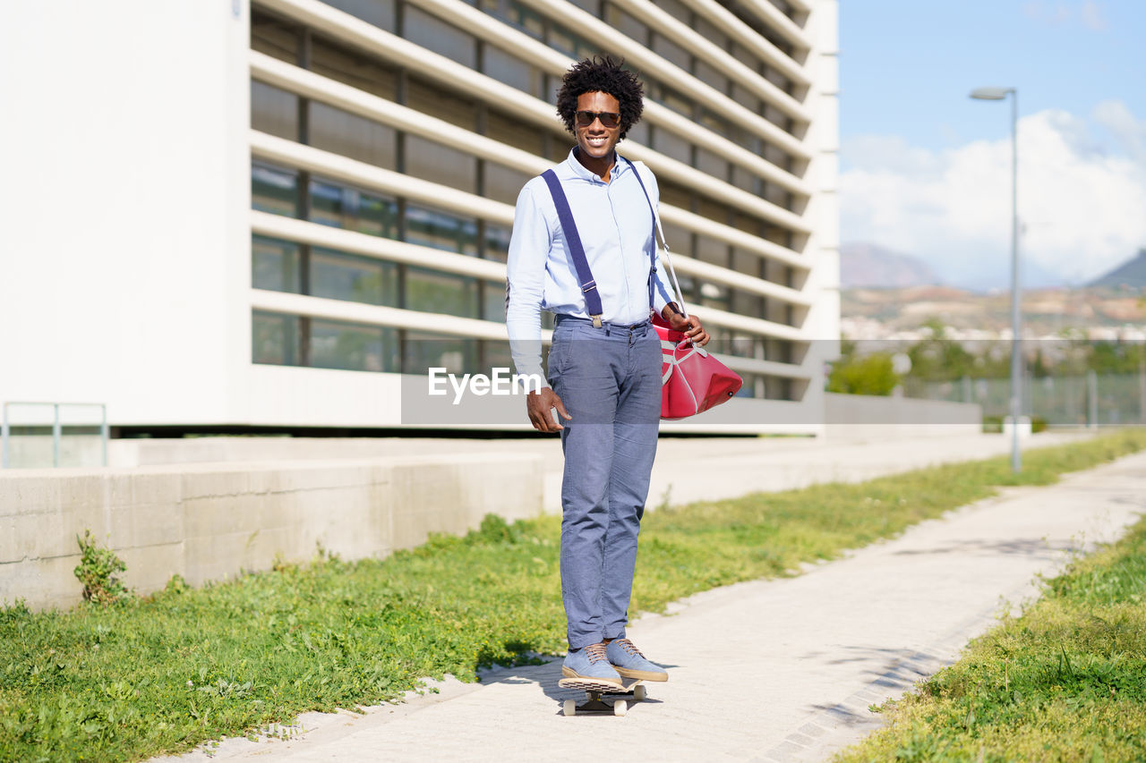 Portrait of young man standing on footpath