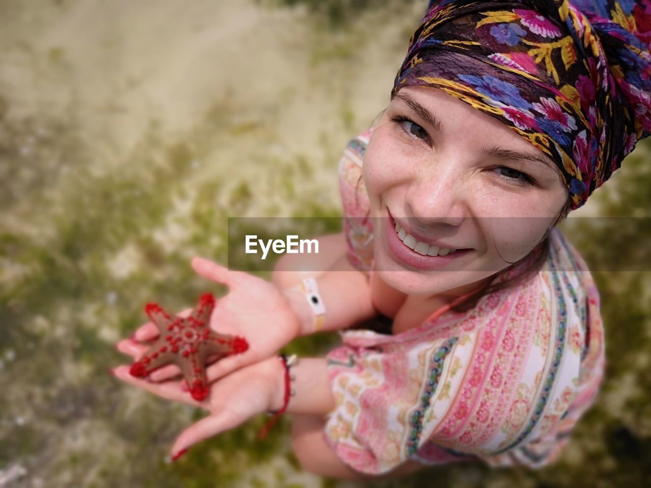 High angle portrait of smiling young woman holding starfish