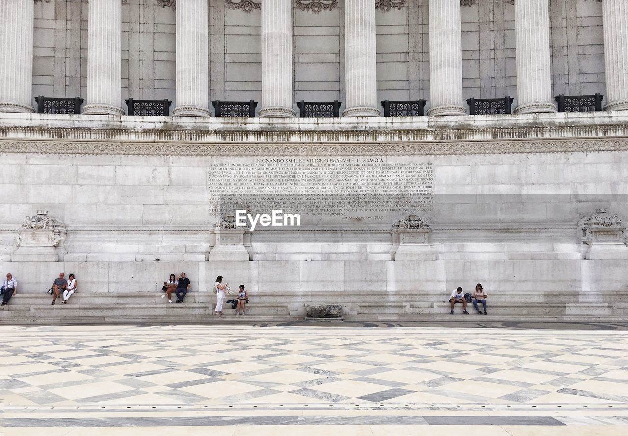 People sitting next to historical building