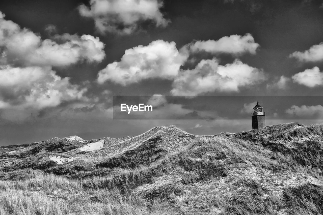 lighthouse, cloud, sky, black and white, monochrome photography, monochrome, guidance, architecture, built structure, environment, mountain, landscape, tower, nature, land, building exterior, scenics - nature, building, security, beauty in nature, protection, day, outdoors, no people, travel destinations, grass, travel, non-urban scene, plant, snow, horizon, tranquility