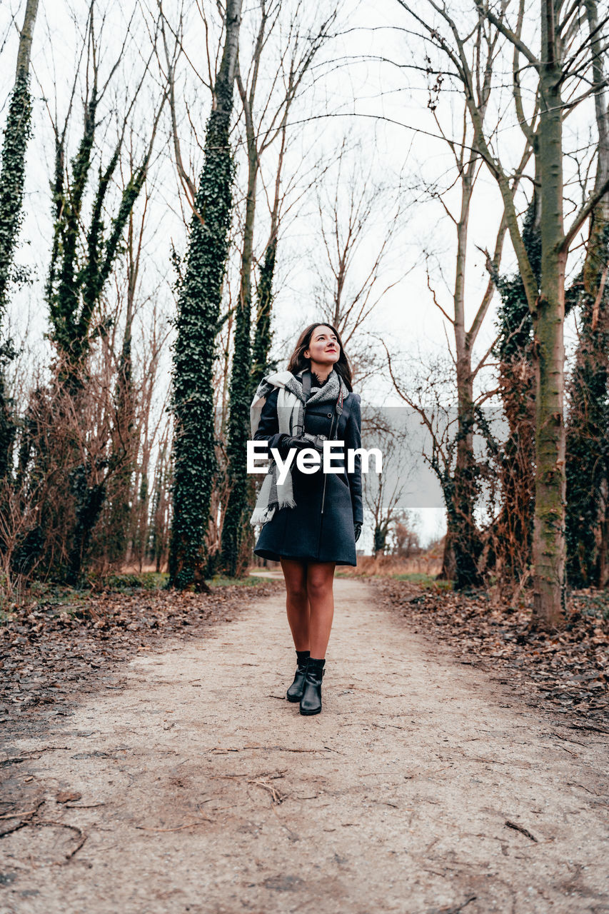 Full length of woman walking on road in forest