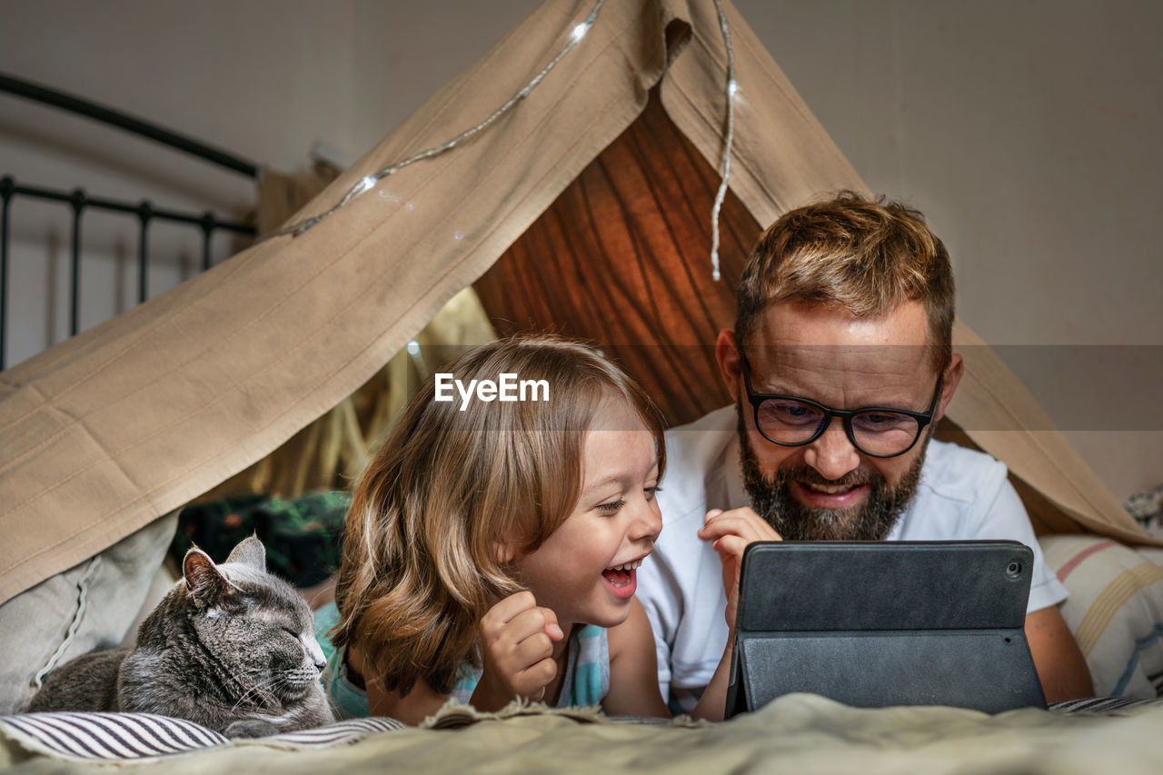 Father and son playing in a teepee tent at home.