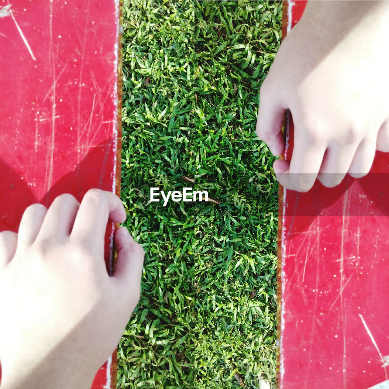 Cropped hands of bench over grassy field