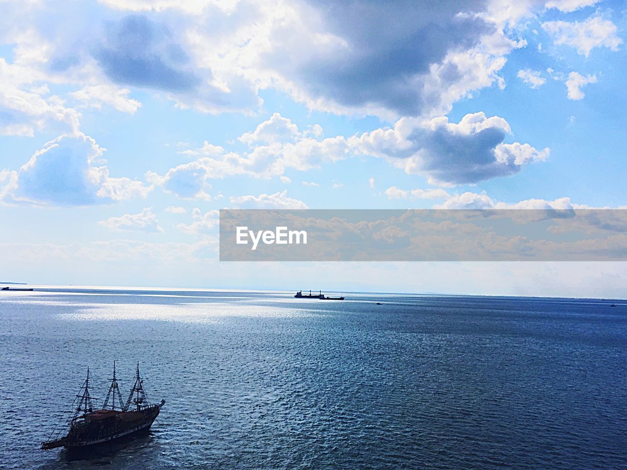 Ship sailing in sea against cloudy sky