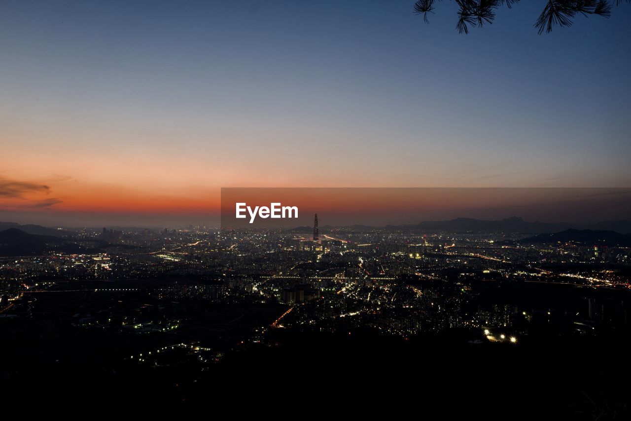 HIGH ANGLE VIEW OF ILLUMINATED CITY BUILDINGS DURING SUNSET