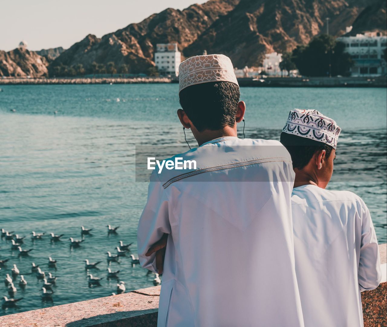 REAR VIEW OF MAN LOOKING AT SEA