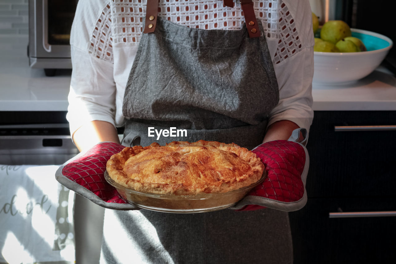 Midsection of woman holding apple pie at home 