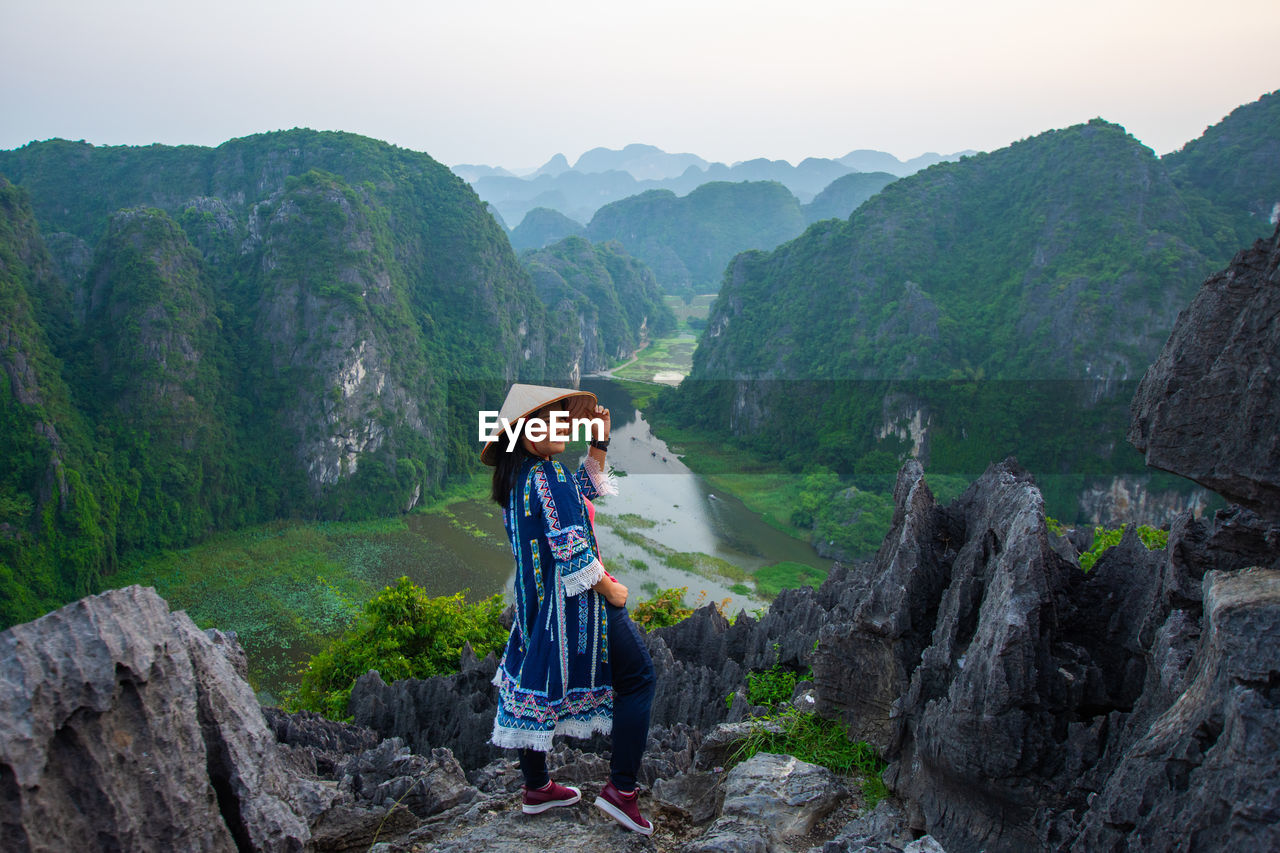 Smiling woman looking away while standing against mountains