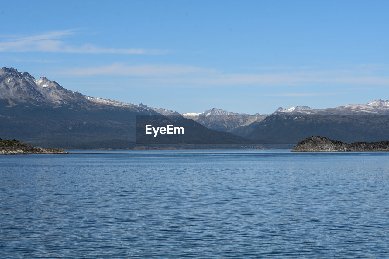 Scenic view of sea and mountains against blue sky