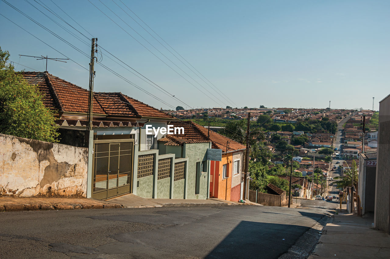 Downhill street view with sidewalk walls and colorful houses on a sunny day at são manuel, brazil.