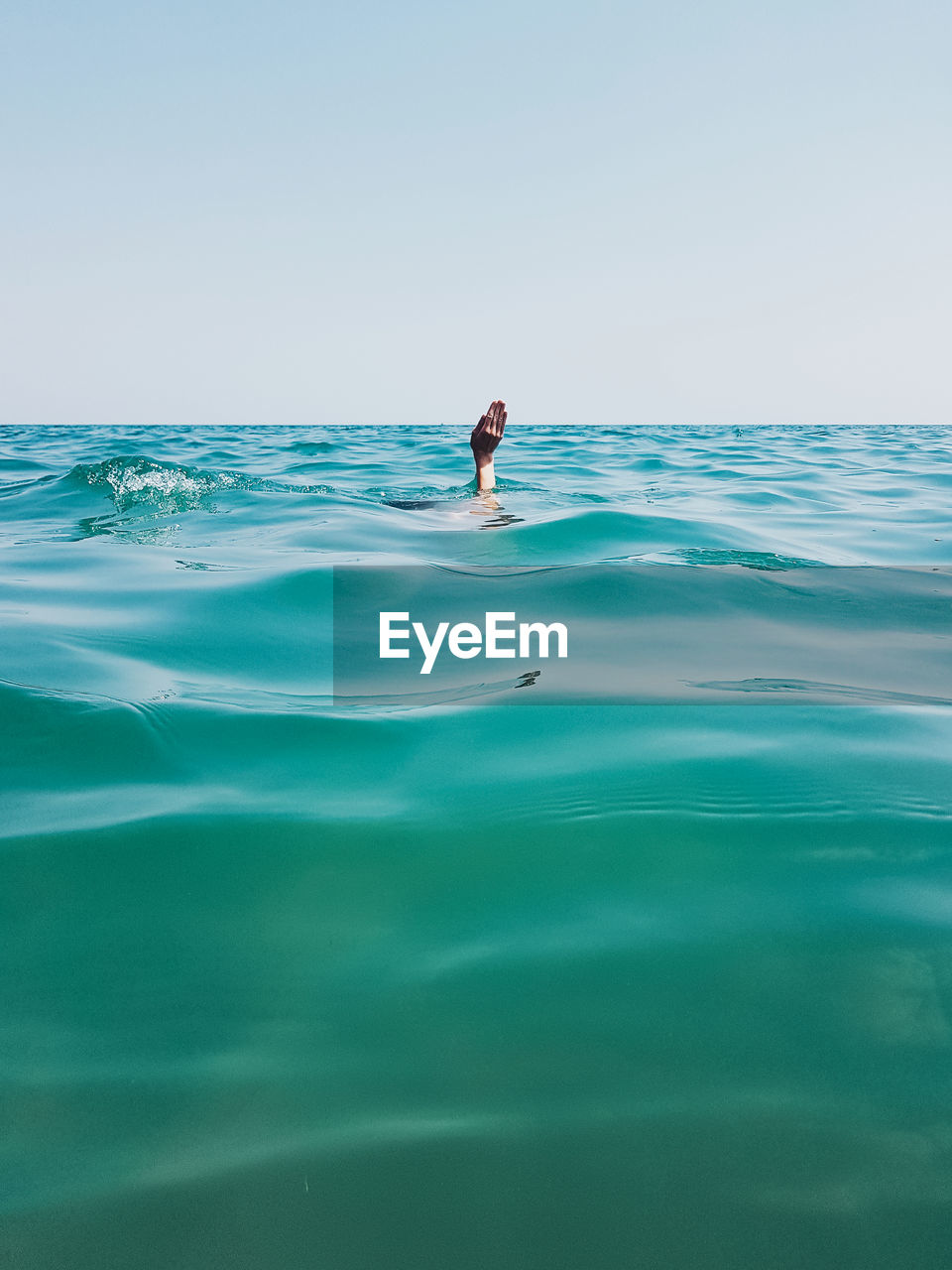 Man drowning in sea against sky