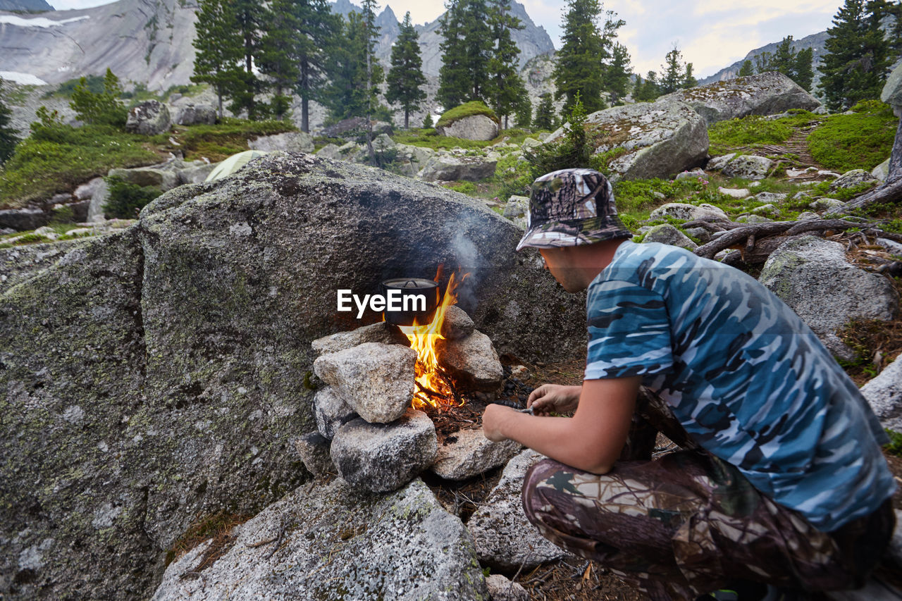 MAN SITTING ON ROCK BY ROCKS