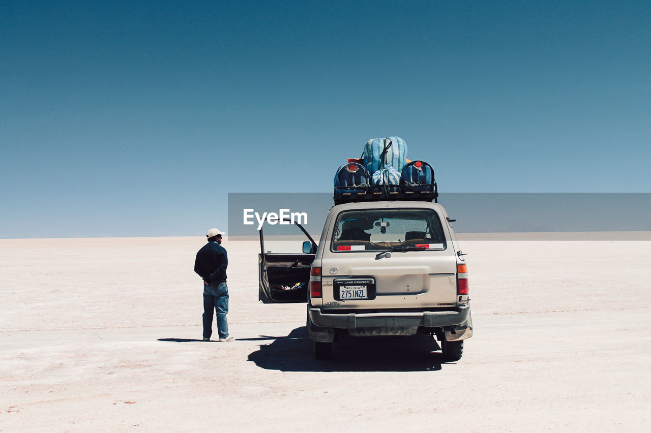 MEN STANDING ON DESERT AGAINST CLEAR SKY