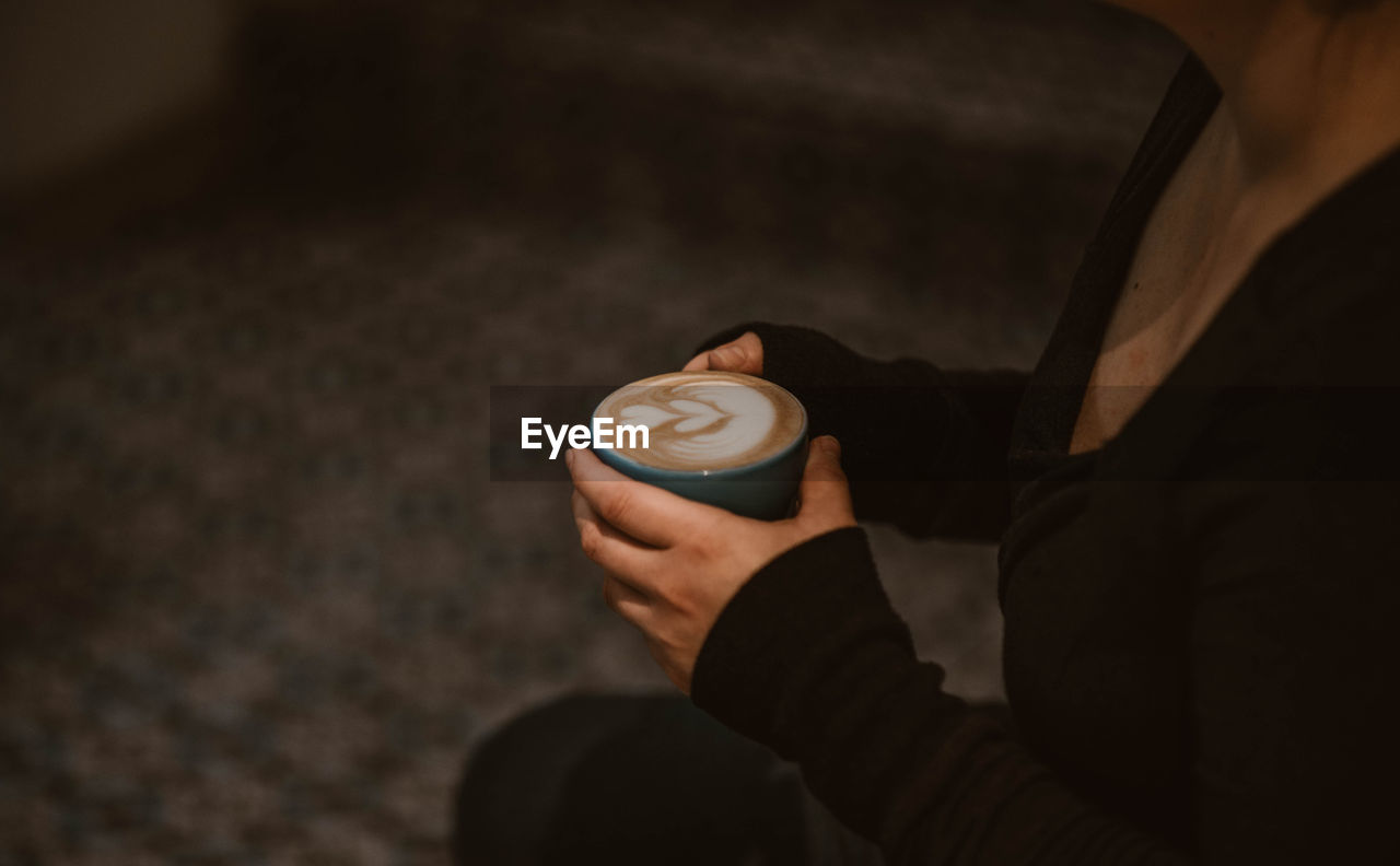 Midsection of woman holding coffee cup at night