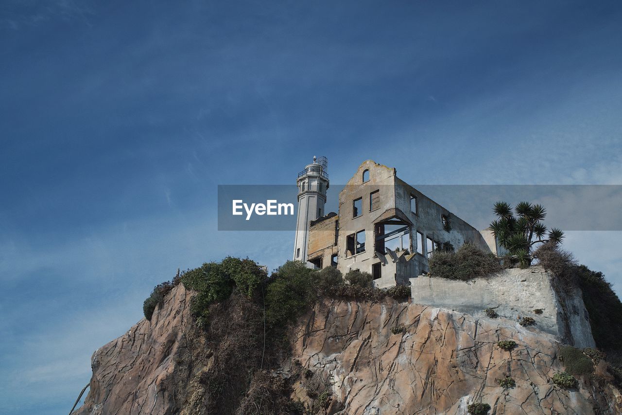 sky, architecture, built structure, mountain, tower, nature, building exterior, cliff, rock, building, mountain range, sea, terrain, history, coast, low angle view, travel destinations, cloud, blue, the past, land, no people, religion, place of worship, travel, outdoors, scenics - nature, belief, landmark, tourism, tree, spirituality, day, castle, beauty in nature, plant, fort, environment