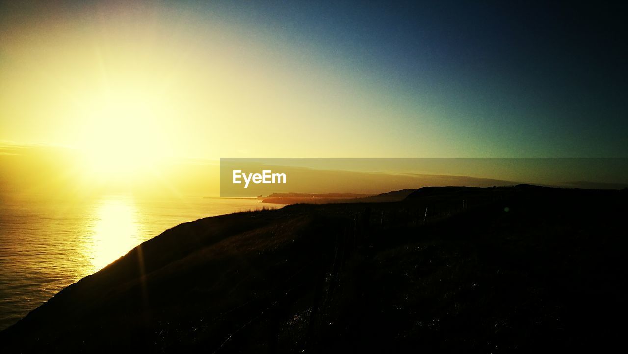 SCENIC VIEW OF BEACH AGAINST SKY AT SUNSET