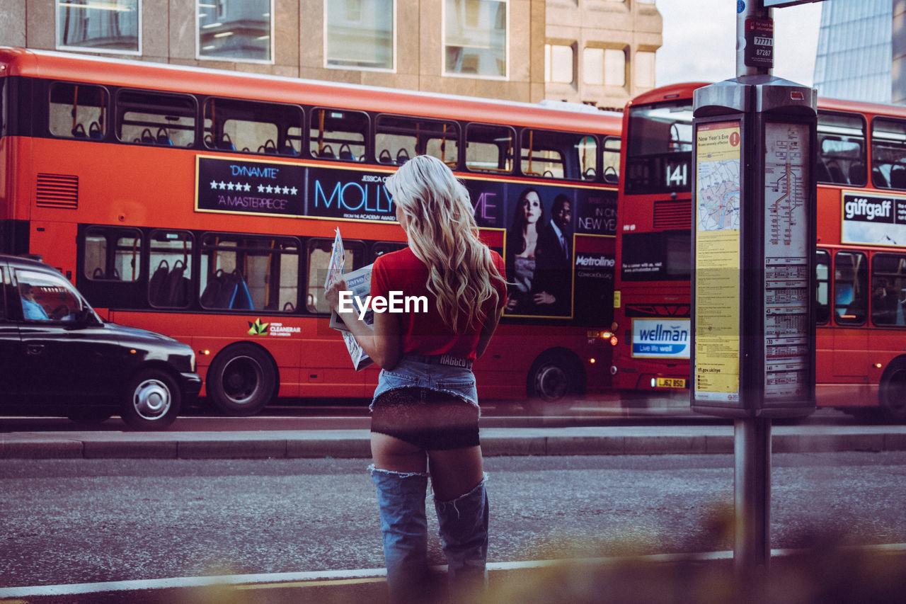 FULL LENGTH REAR VIEW OF WOMAN STANDING ON ROAD