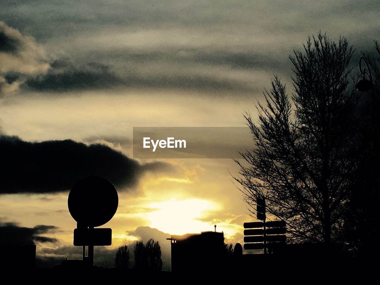 SILHOUETTE OF BUILDING AGAINST CLOUDY SKY AT SUNSET