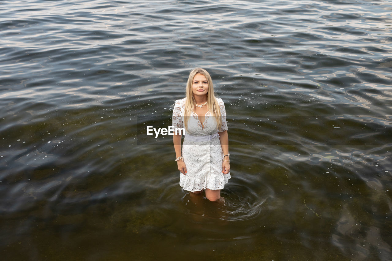 PORTRAIT OF YOUNG WOMAN SMILING IN LAKE