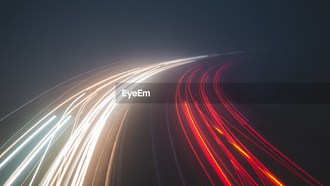 Light trails on road against sky at night