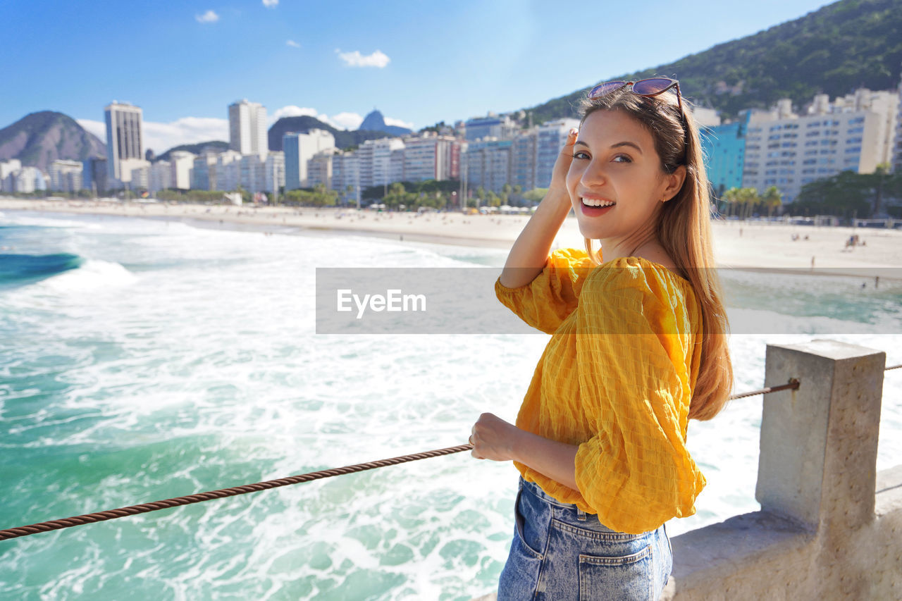 Portrait of stylish cheerful girl with waving ocean water of copacabana beach, rio de janeiro brazil