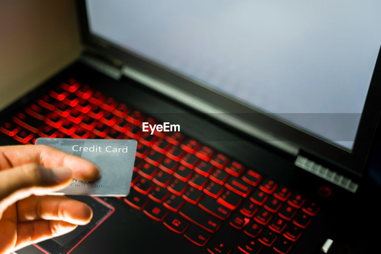 Closeup of a hand holding credit card.businessman use laptop online payments with plastic debit card