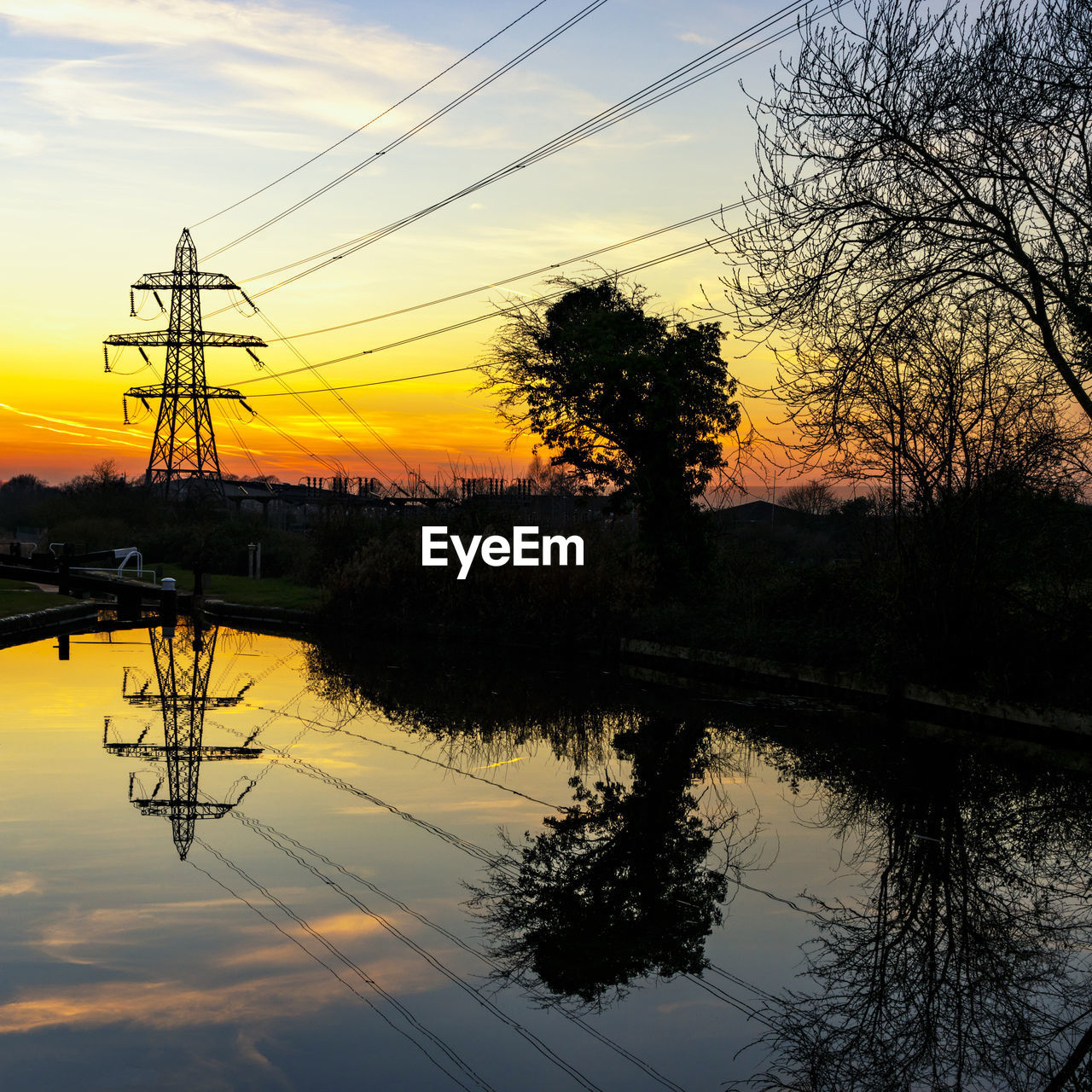 SILHOUETTE TREES BY LAKE AGAINST ORANGE SKY