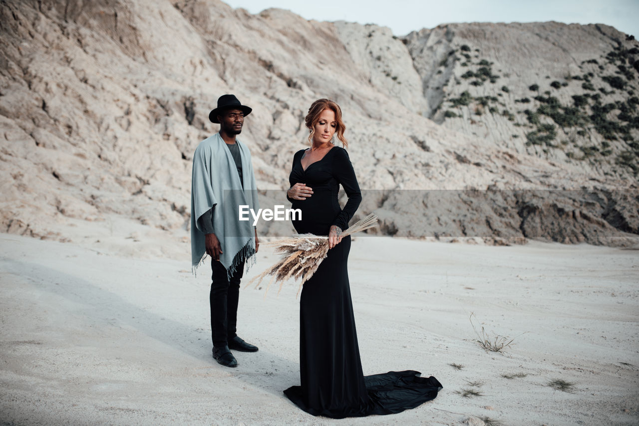 Full length of couple standing on sand in desert