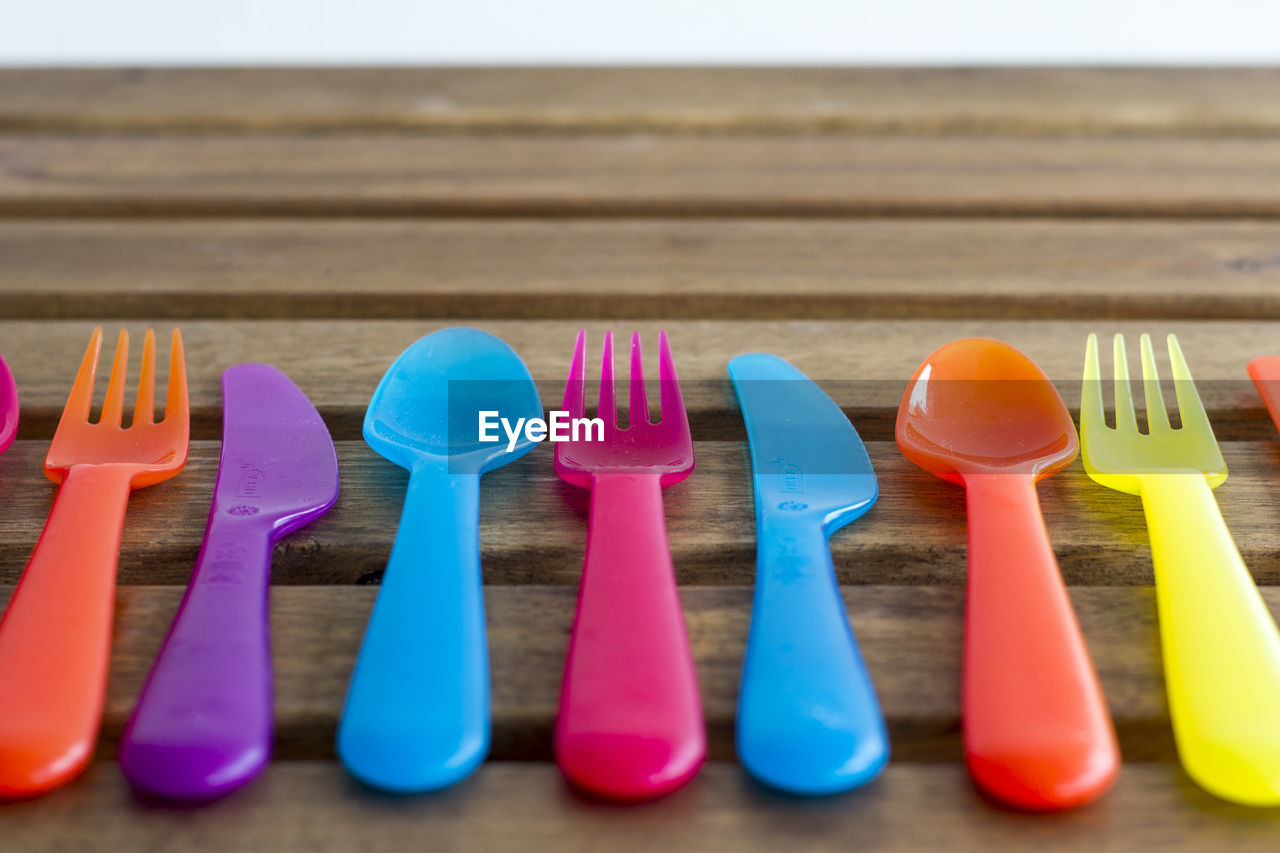 Close-up of colorful plastic eating utensils on wooden table