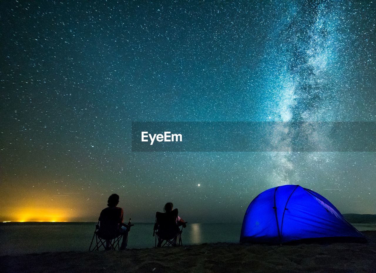 People sitting against star field at night