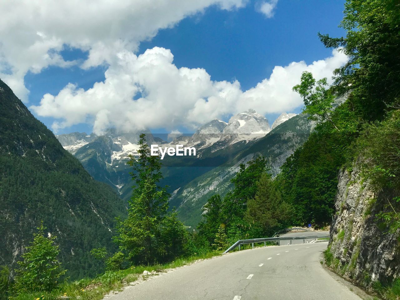 Road amidst trees and mountains against sky