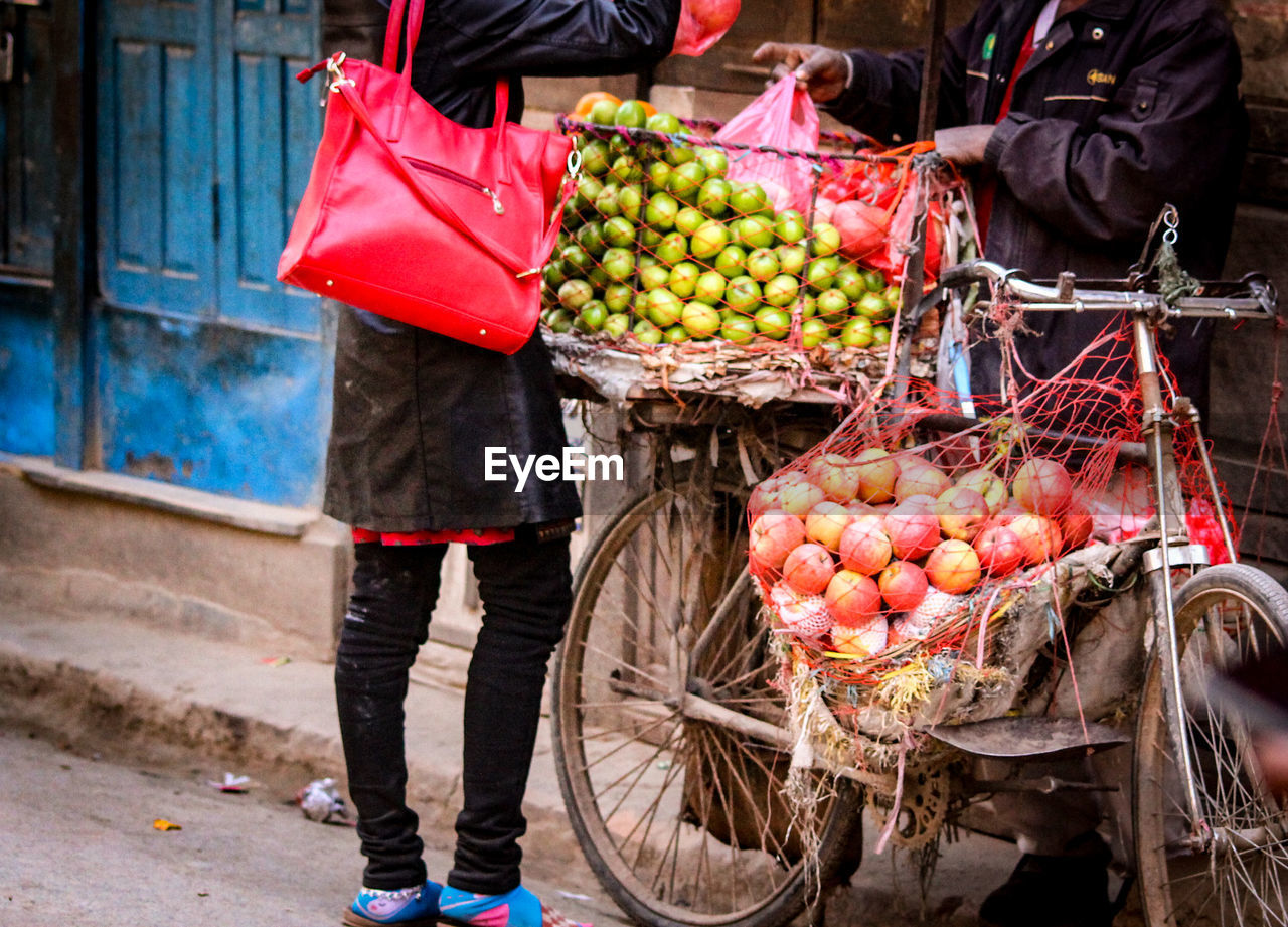 LOW SECTION OF WOMAN STANDING BY FRUITS AT MARKET