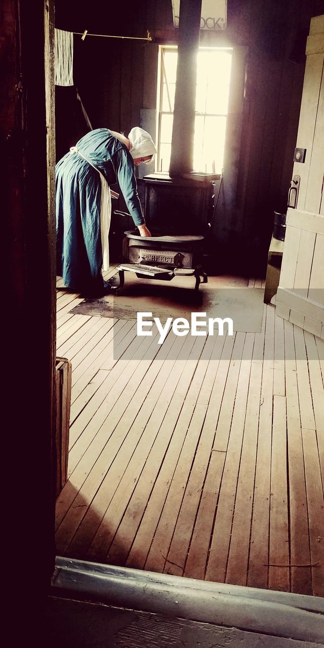 SIDE VIEW OF MAN WORKING ON WOODEN FLOOR