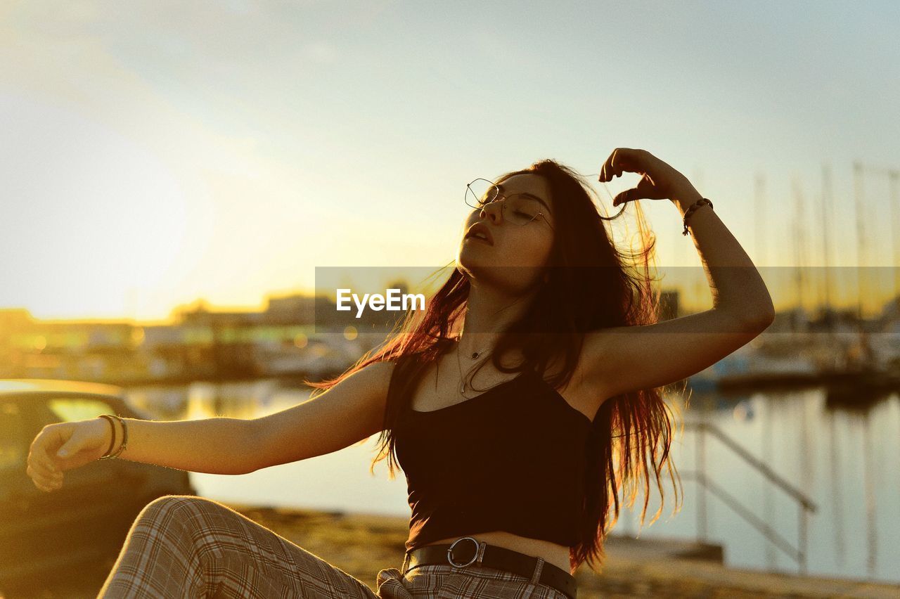 Woman posing outdoors against sky during sunset