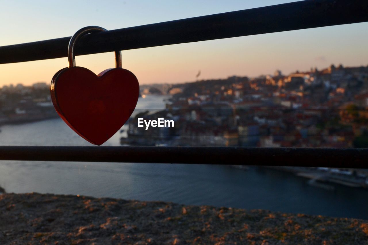 CLOSE-UP OF PADLOCKS HANGING ON RAILING BY RIVER