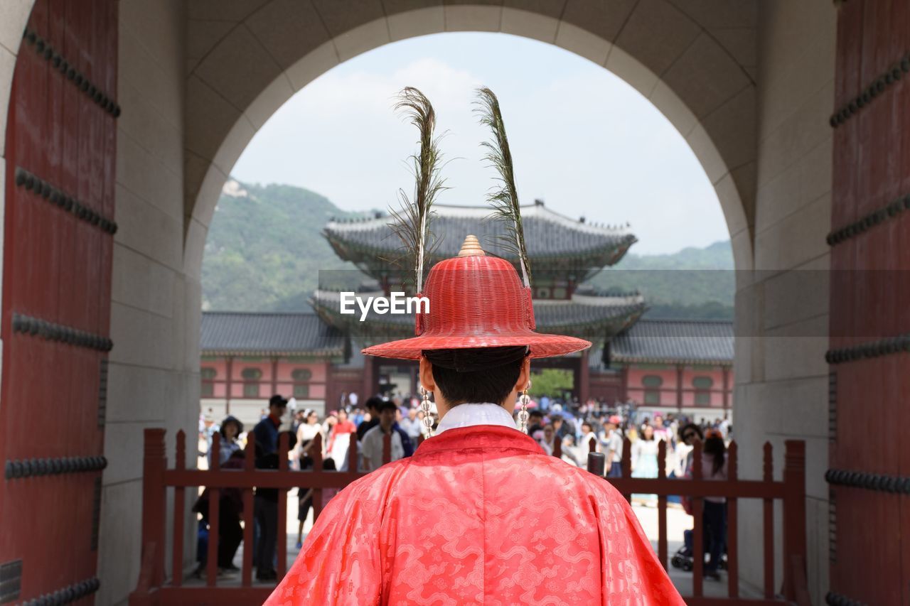Rear view of man in traditional clothing standing against shrine