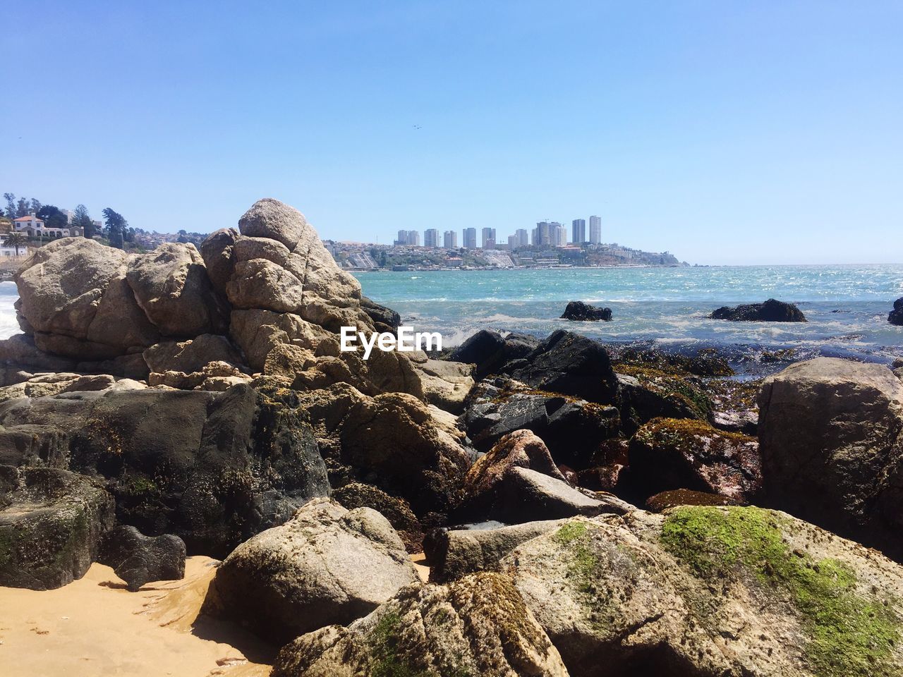 View of sea and cityscape against clear blue sky