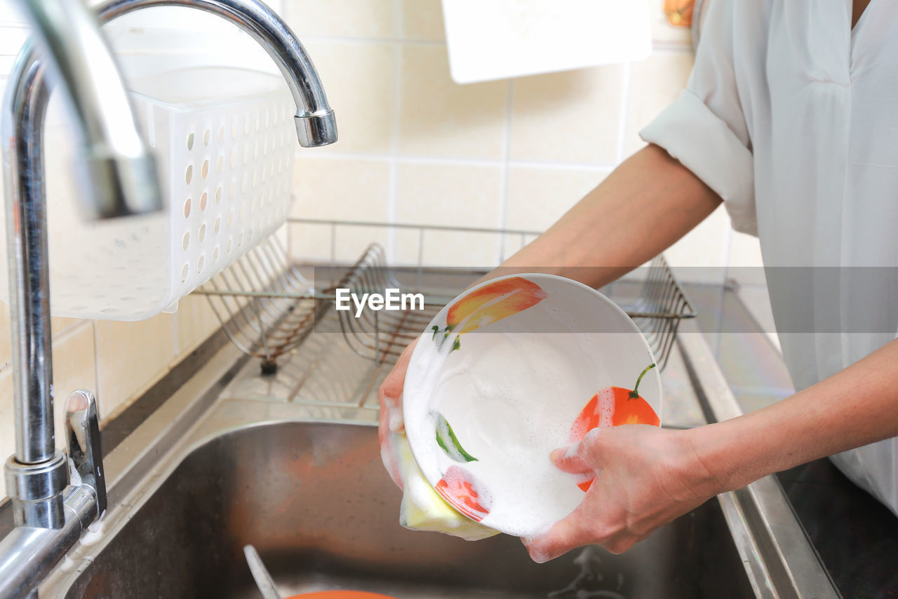 Midsection of woman washing bowl at home