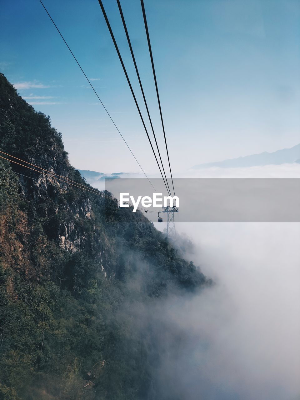 sky, mountain, cable, nature, cloud, scenics - nature, environment, electricity, landscape, beauty in nature, mountain range, no people, fog, land, travel, transportation, outdoors, technology, day, travel destinations, tranquil scene, tranquility, blue, cable car, power line, non-urban scene, power supply, rock, morning, sunlight