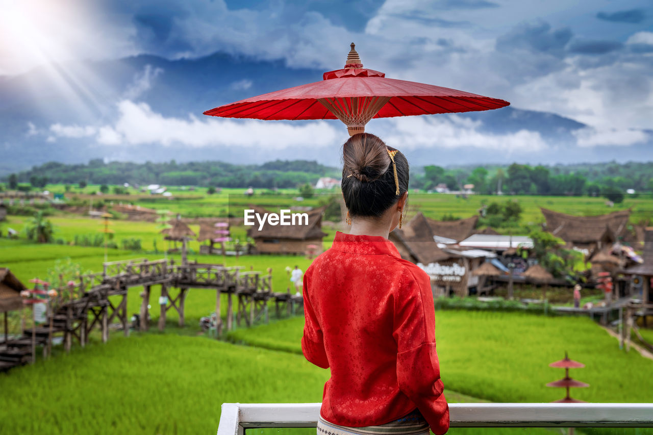 Rear view of woman holing umbrella standing against sky