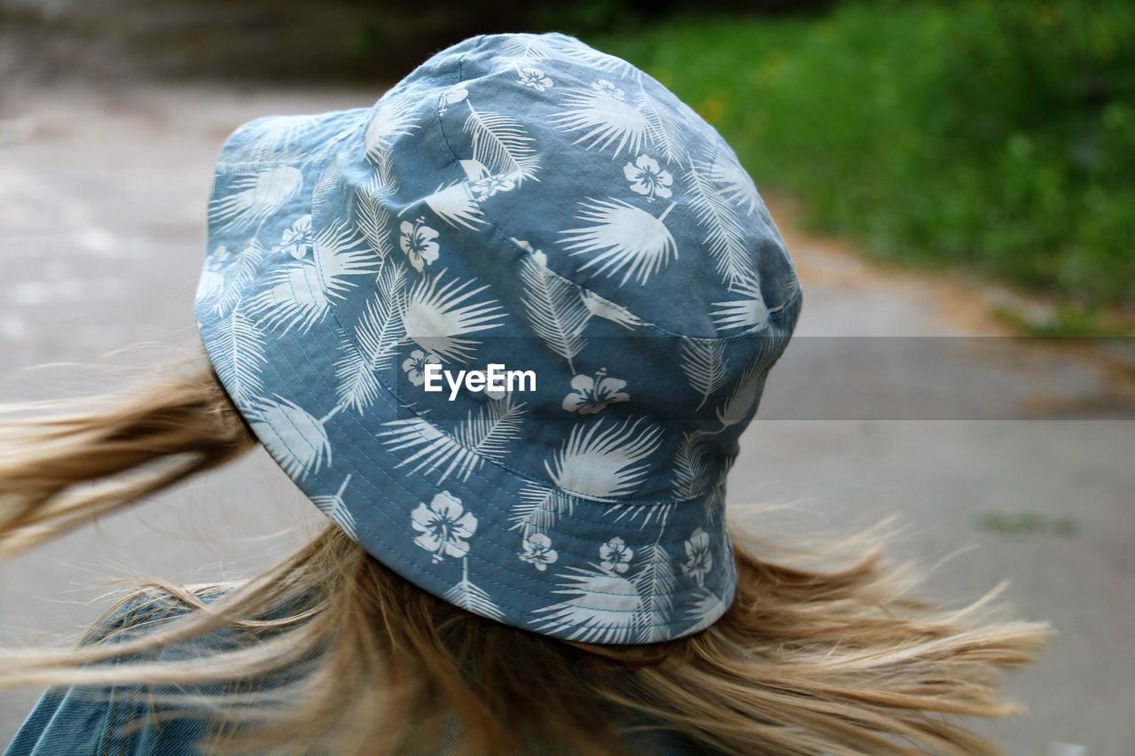 Close-up of woman wearing bucket hat while standing on footpath