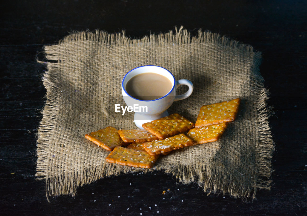 A cup of tea with biscuits on old wooden dark background