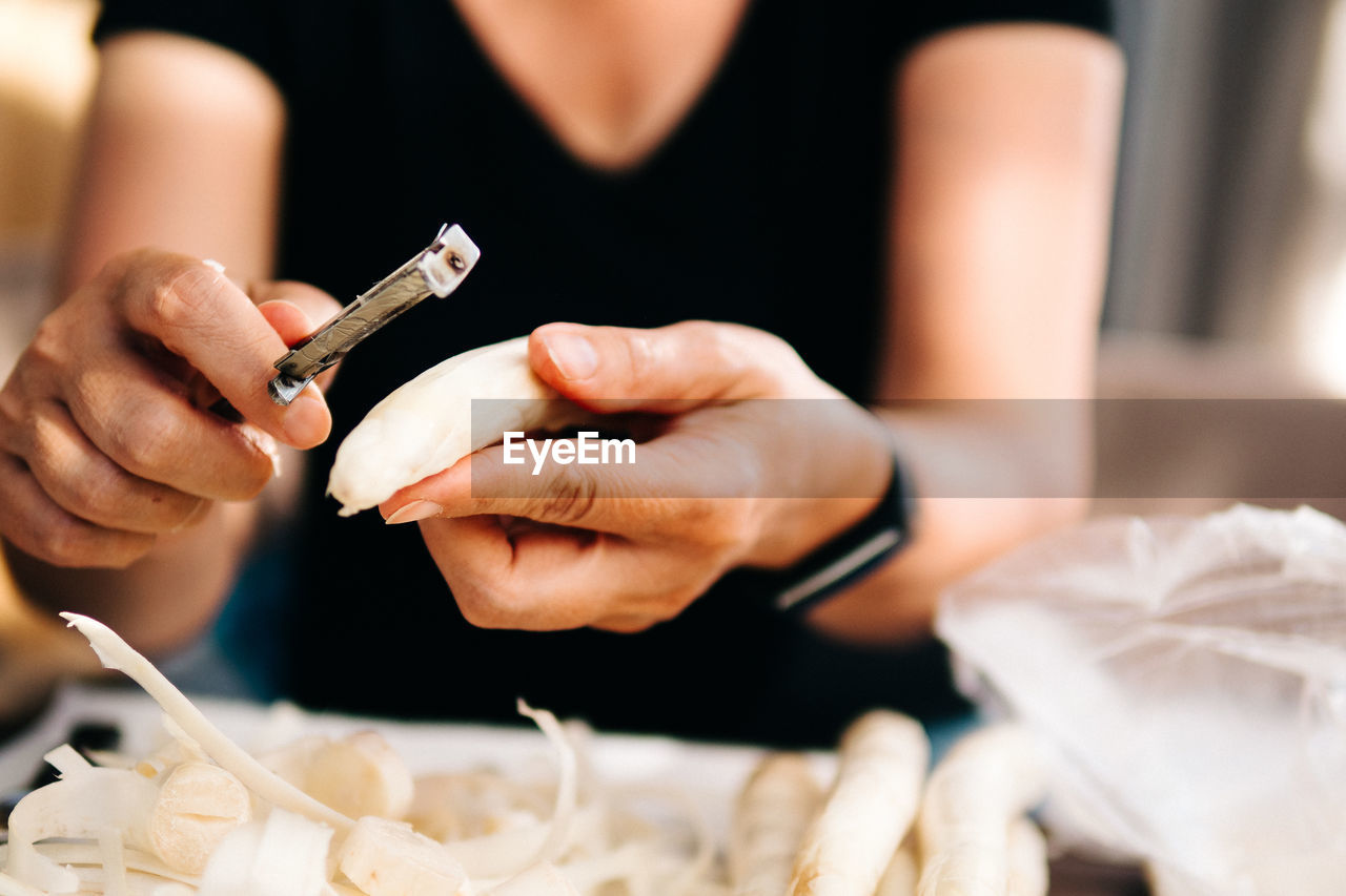 Midsection of woman peeling vegetable