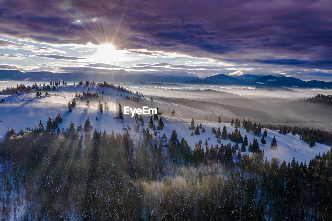 Scenic view of snow covered landscape against sky during sunset