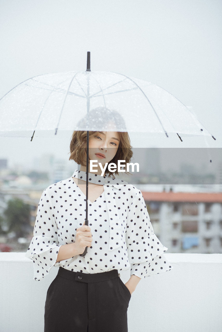 Young woman with umbrella standing on terrace