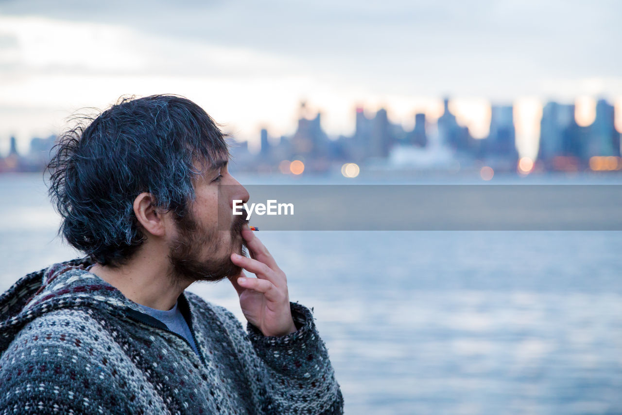 PORTRAIT OF YOUNG MAN LOOKING AWAY AT SEA