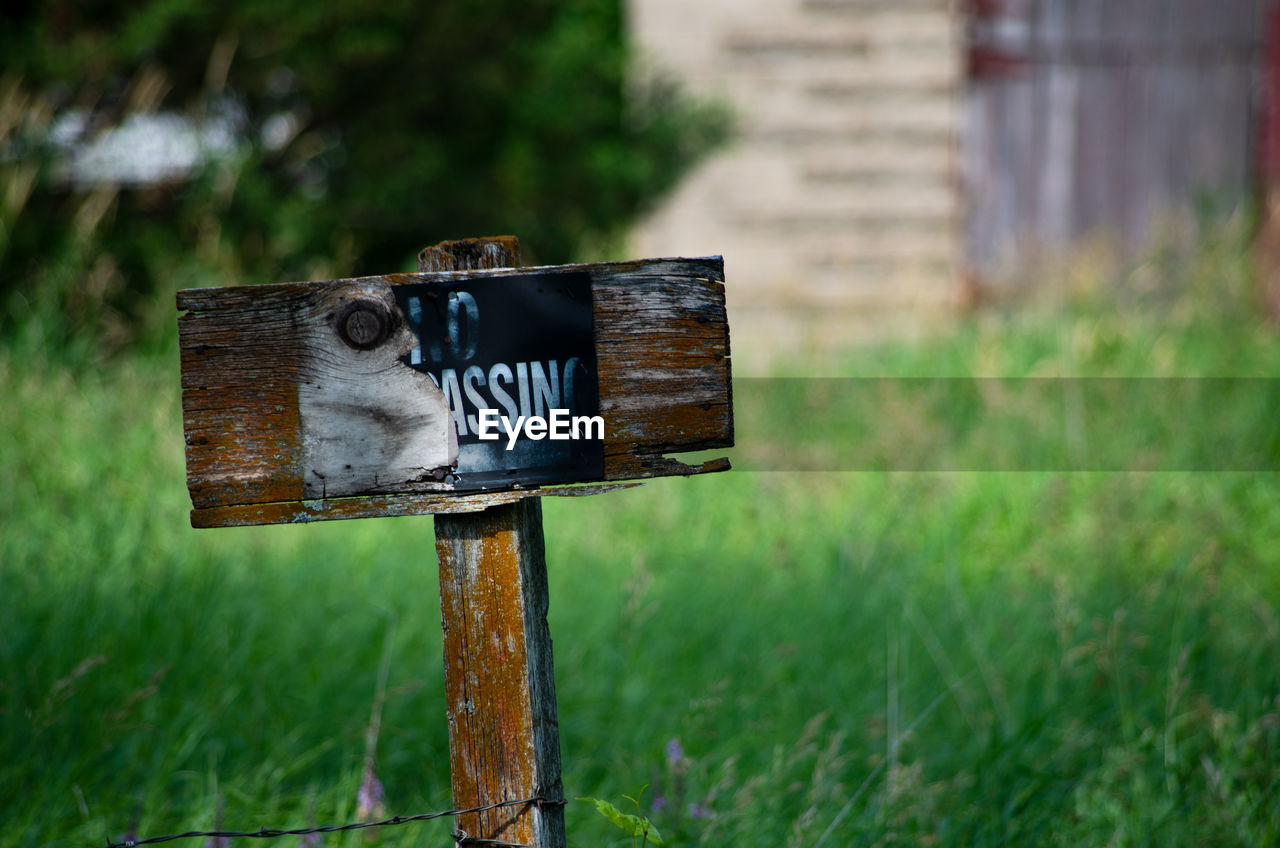 CLOSE-UP OF INFORMATION SIGN ON FIELD AGAINST BLURRED BACKGROUND