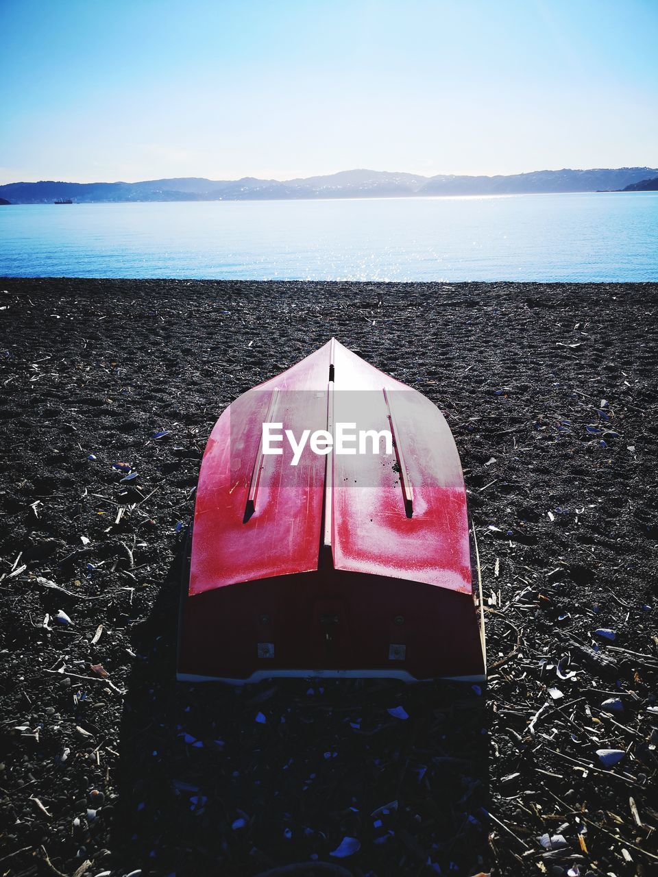 Red boat on sea shore against sky