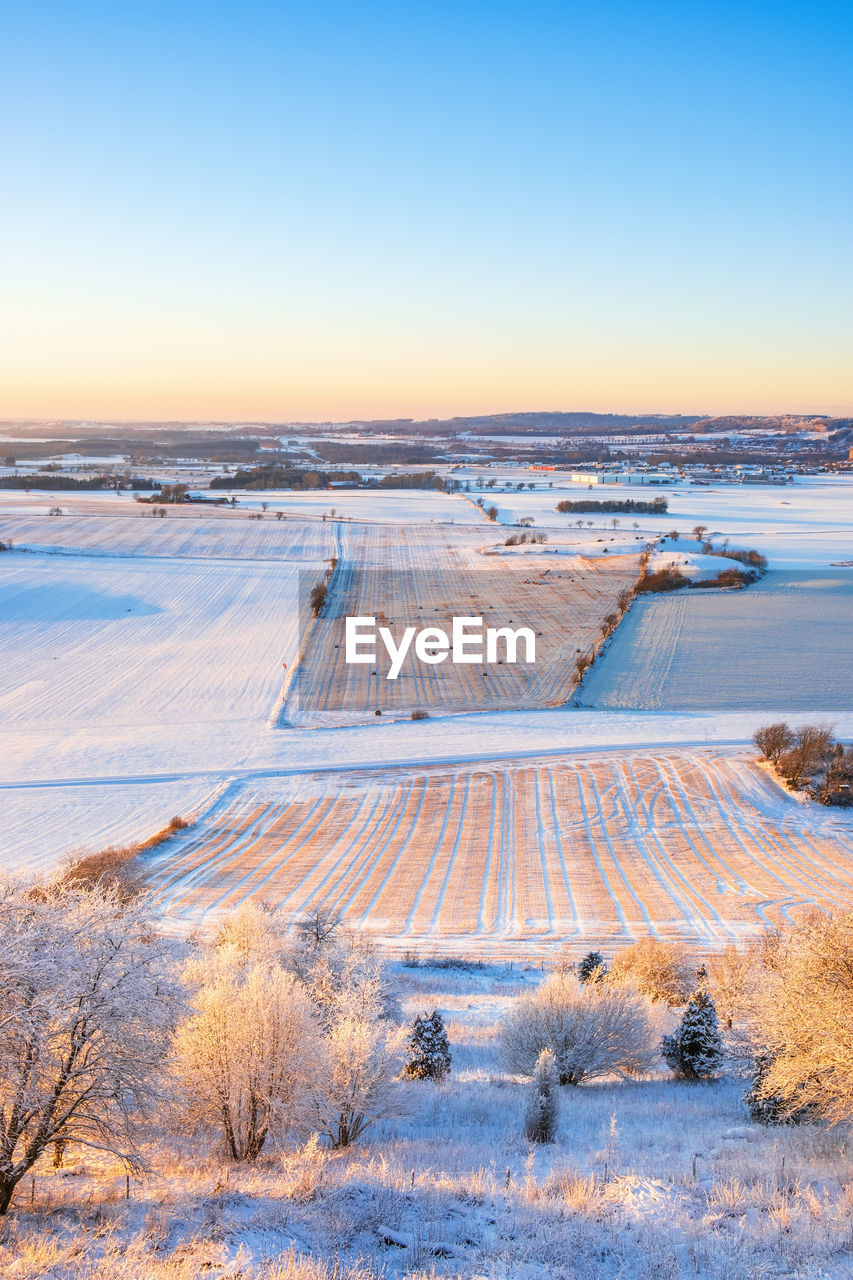 Scenic view of snow covered land during sunset